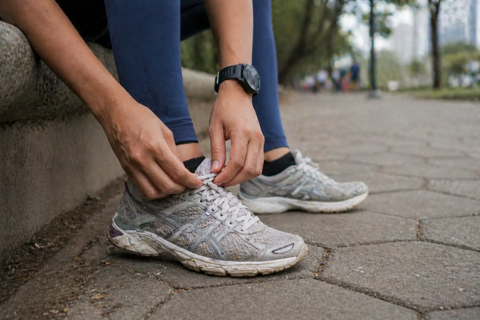 Pessoa amarrando o cadarço do tênis antes de uma caminhada